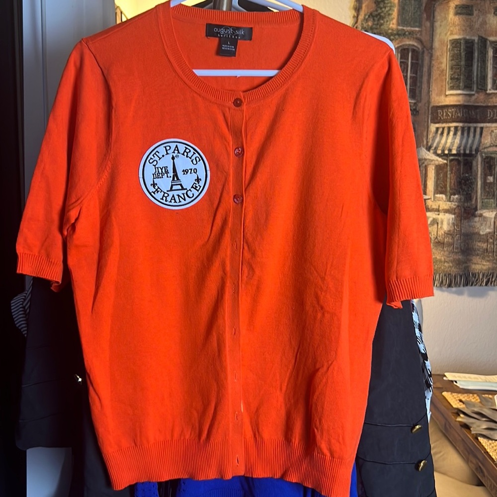 Orange short sleeve sweater with a patch on front